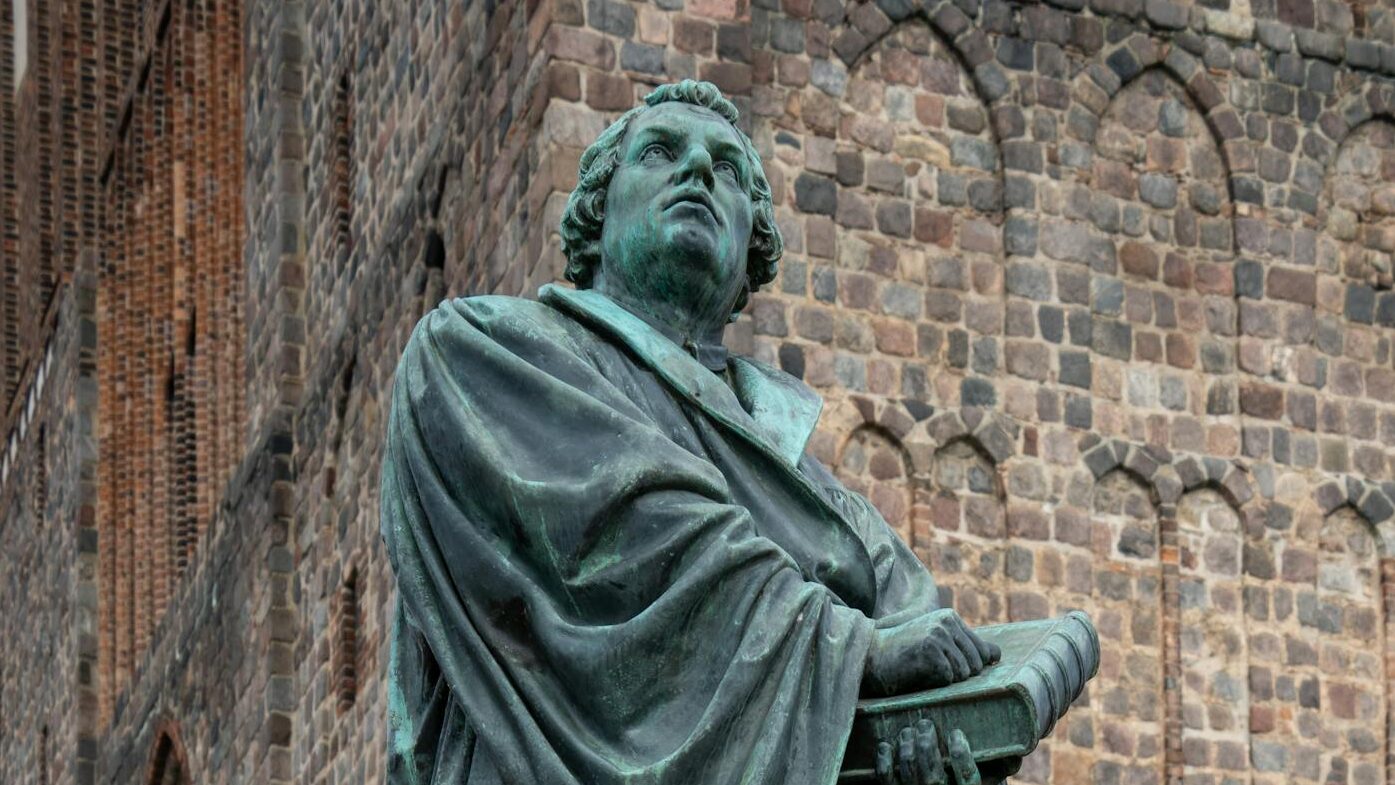 Statue of Martin Luther outside a historic brick church, symbolizing the Protestant Reformation.