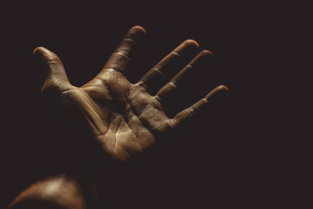 A powerful silhouette of an outstretched palm against a dark background, evoking emotion.